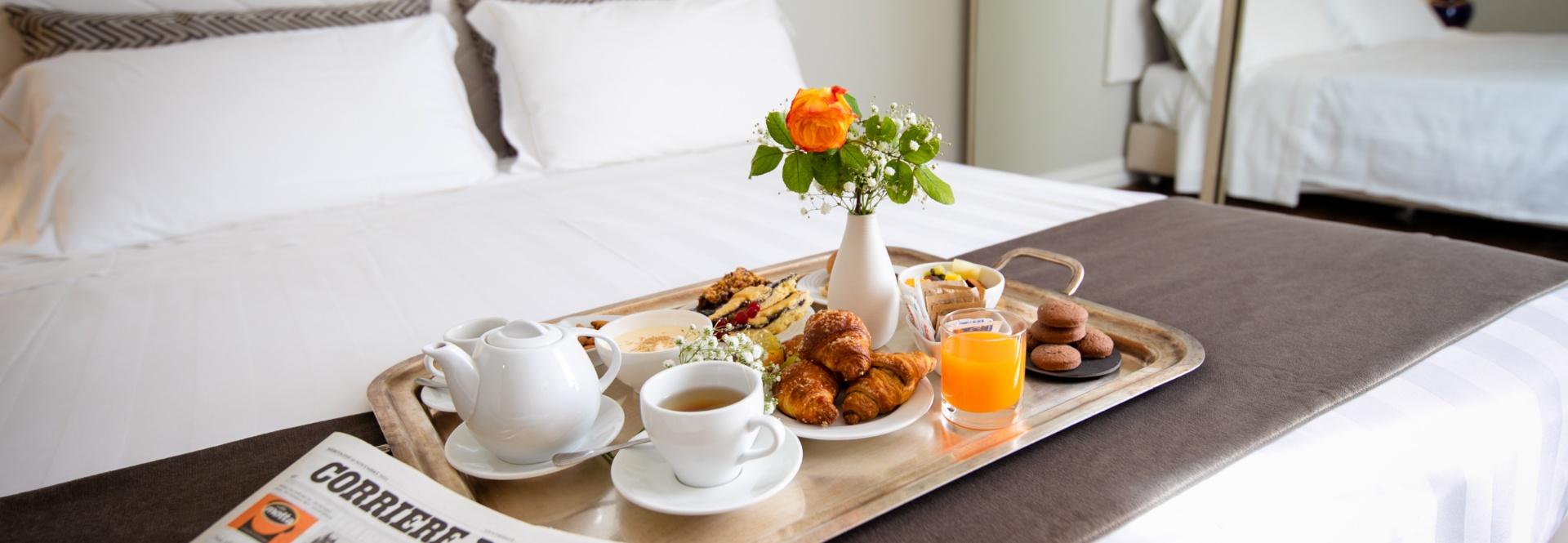 Colazione a letto con tè, croissant, succo d'arancia e fiori freschi.