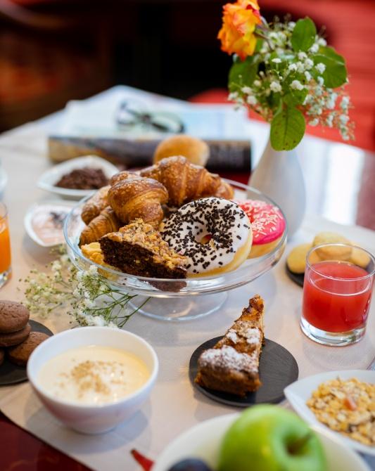 Breakfast with pastries, croissants, juice, and flowers on table.
