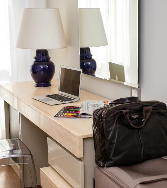 Desk with laptop, lamp, magazine, and leather bag.
