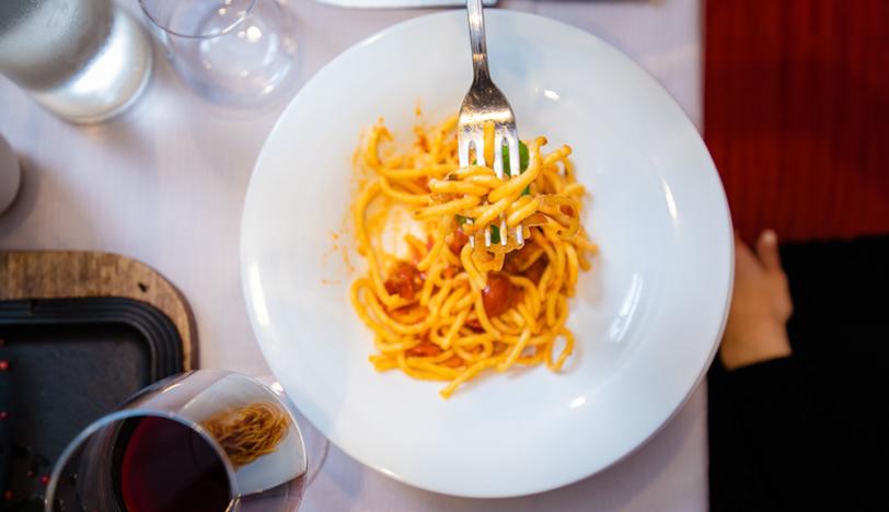 Plate of spaghetti with tomato sauce and a glass of red wine.