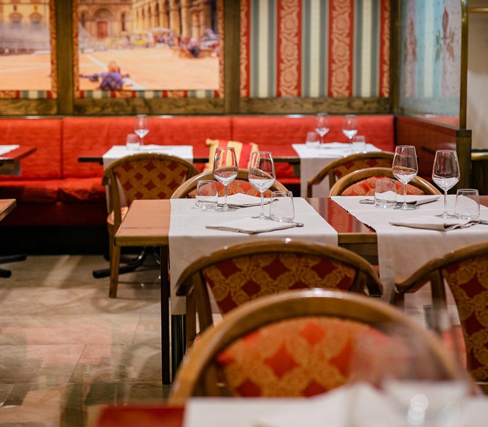 Ristorante elegante con tavoli apparecchiati, sedie rosse e decorazioni classiche.