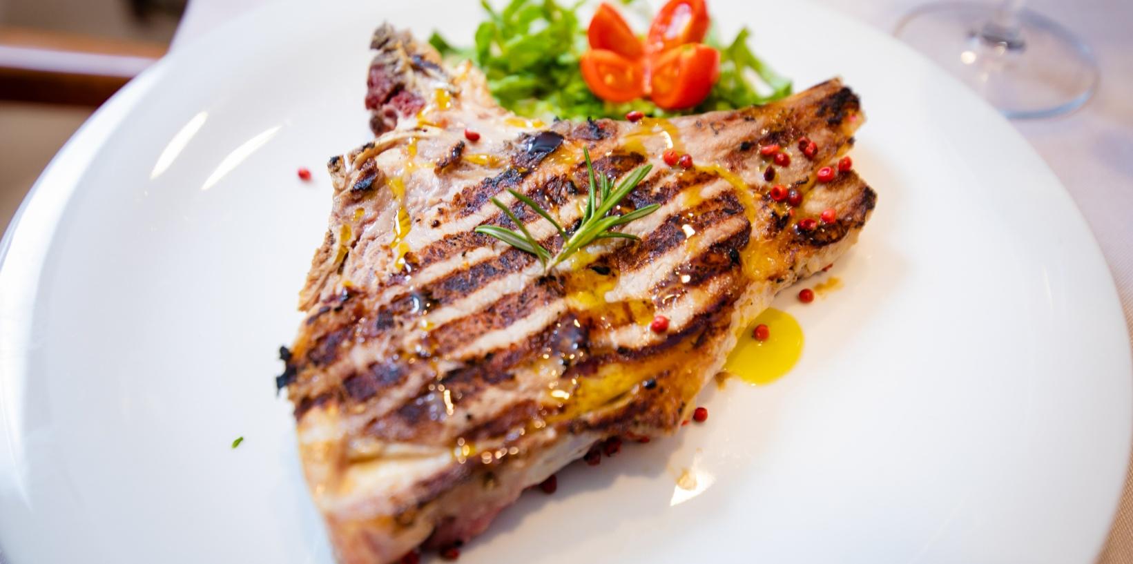 Bistecca grigliata con pepe rosa, rosmarino e contorno di pomodorini e rucola.