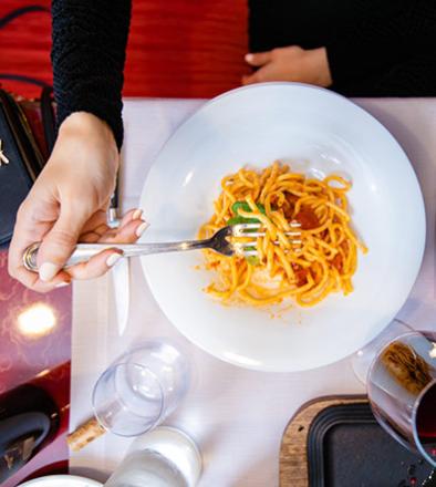 Donna in rosso con prosecco e tagliere di formaggi e frutta.
