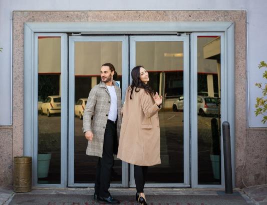 Due persone eleganti escono da un edificio attraverso una porta a vetri.