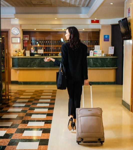 Donna in hotel con valigia, cammina verso la reception.
