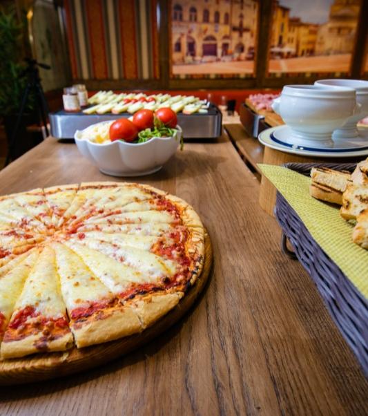Pizza margherita su tavolo di legno con insalata e pane a buffet.