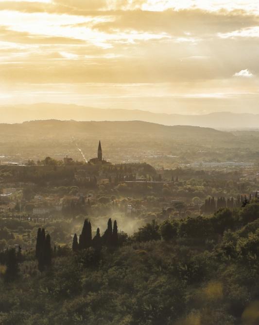 Hilly landscape at sunset with a distant bell tower.