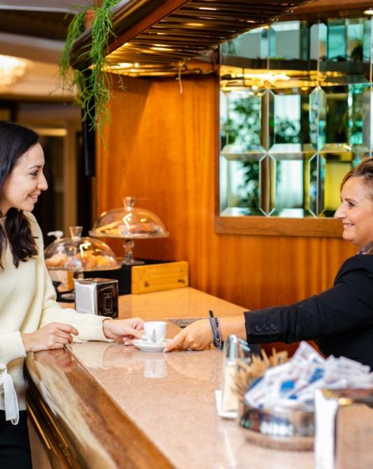 Donna al bar riceve un caffè da una barista sorridente.