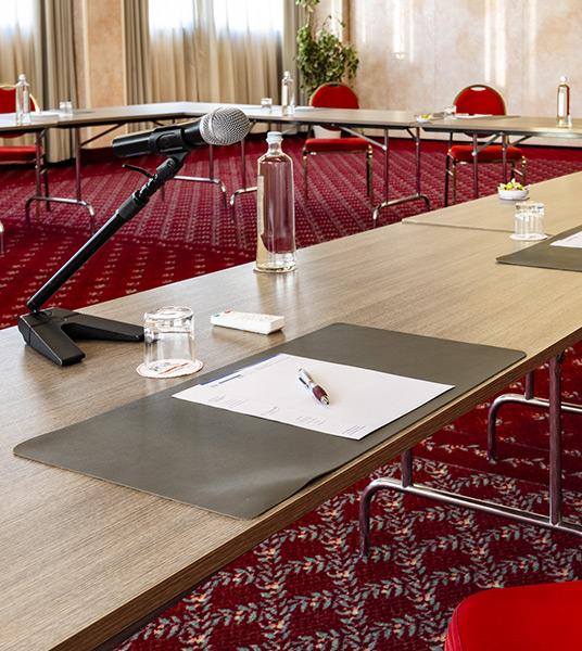 Due persone in abiti formali discutono in una sala conferenze vuota.