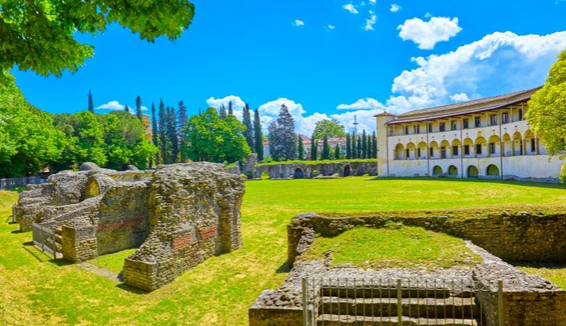Roman ruins and historic palace in a green park.