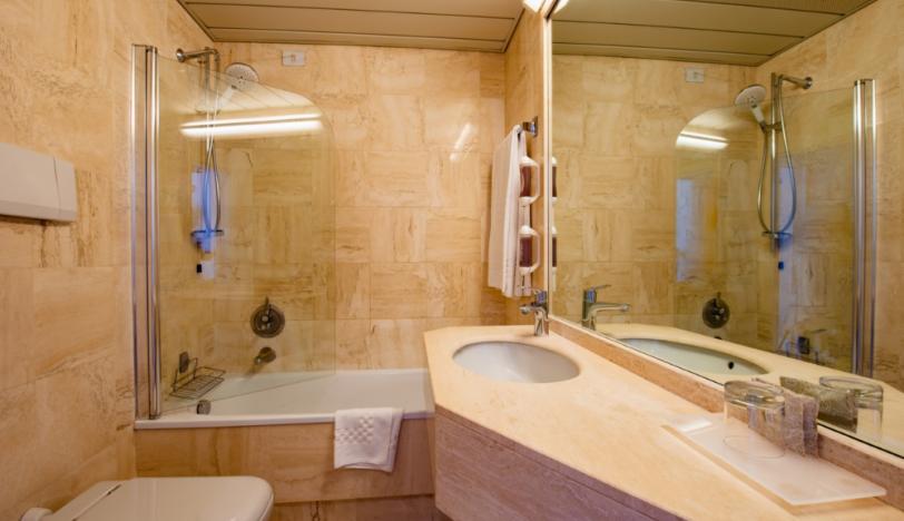 Elegante bagno moderno con vasca, lavabo in marmo e ampio specchio.
