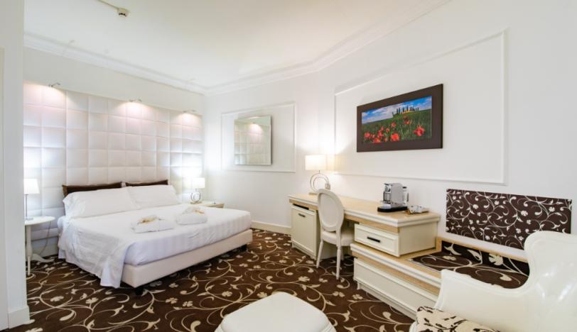 Camera elegante con letto matrimoniale, scrivania e decorazioni floreali.