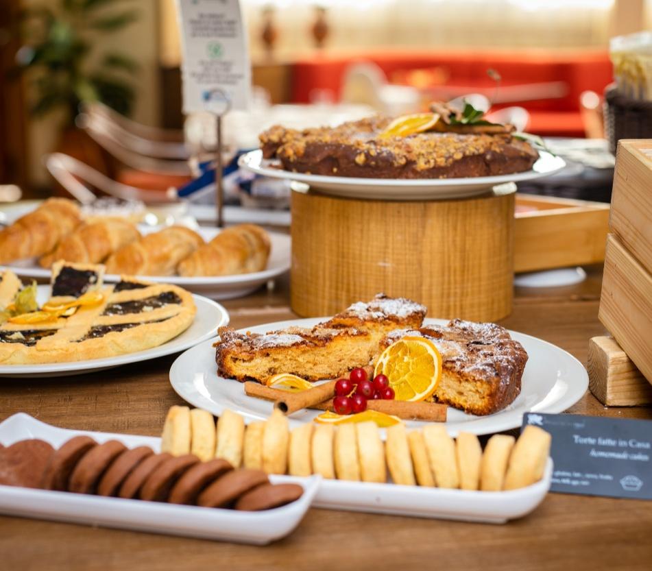 Buffet di dolci con torte, biscotti e croissant su un tavolo.