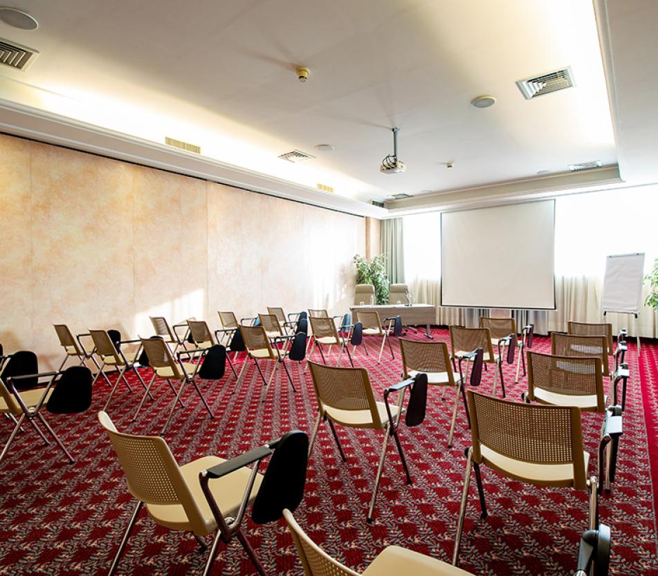 Sala riunioni moderna con tavolo, sedie, bevande e piante decorative.